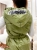Tył zielonej pikowanej kamizelki wiosennej, widoczne poziome przeszycia i luźny krój kaptura.